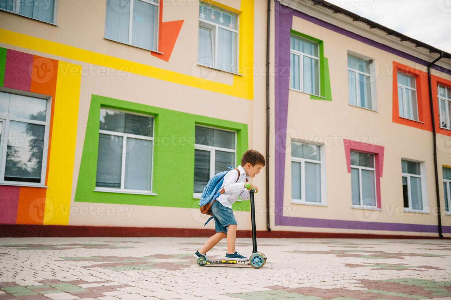 Boy goes to school on a scooter. Children back to school scoote.Childschool riding a scooter. Back to school. Happy children. Happy childhood lifestyle. Student goes to school photo