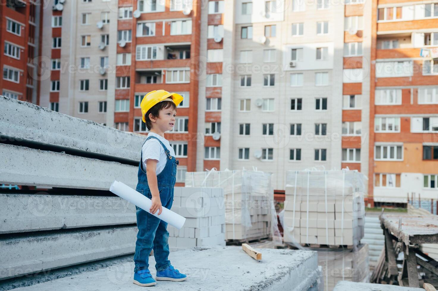 Architect in helmet writing something near new building. little cute boy on the building as an architect photo