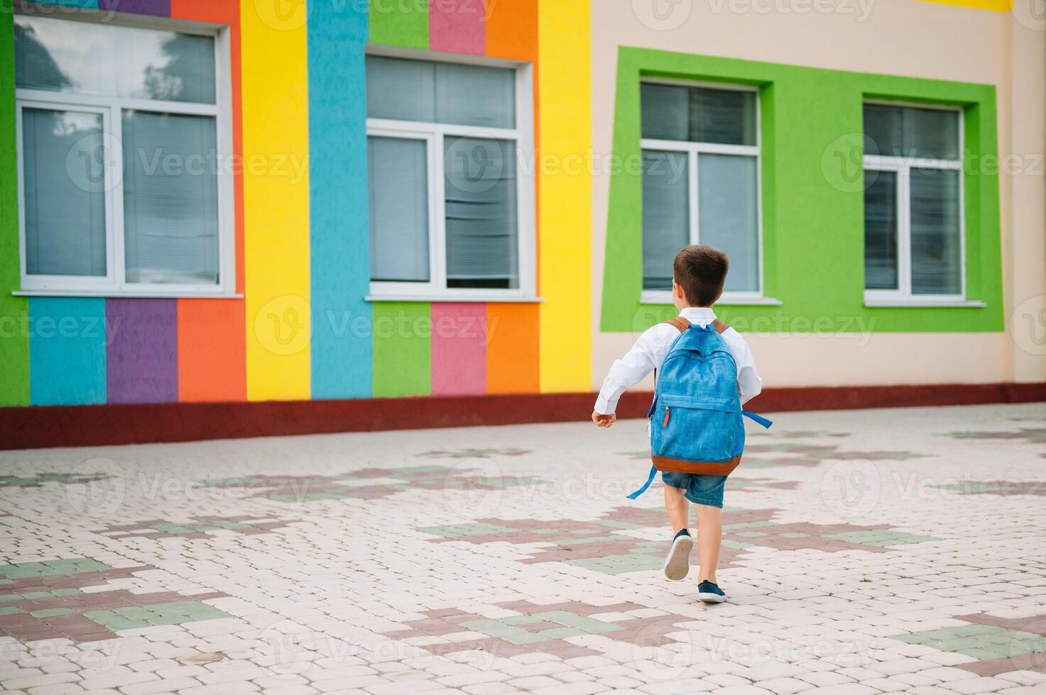 Little boy going back to school. Child with backpack and books on first school day. Back view. School concept. Back to school. photo