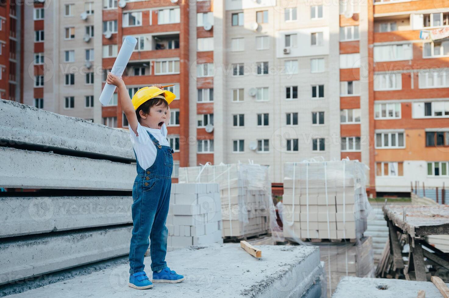 Architect in helmet writing something near new building. little cute boy on the building as an architect photo