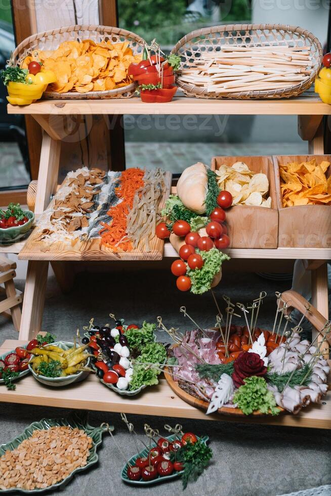 Antipasti board with various cheese and meat snacks with hummus and olives on wooden round board on black table photo