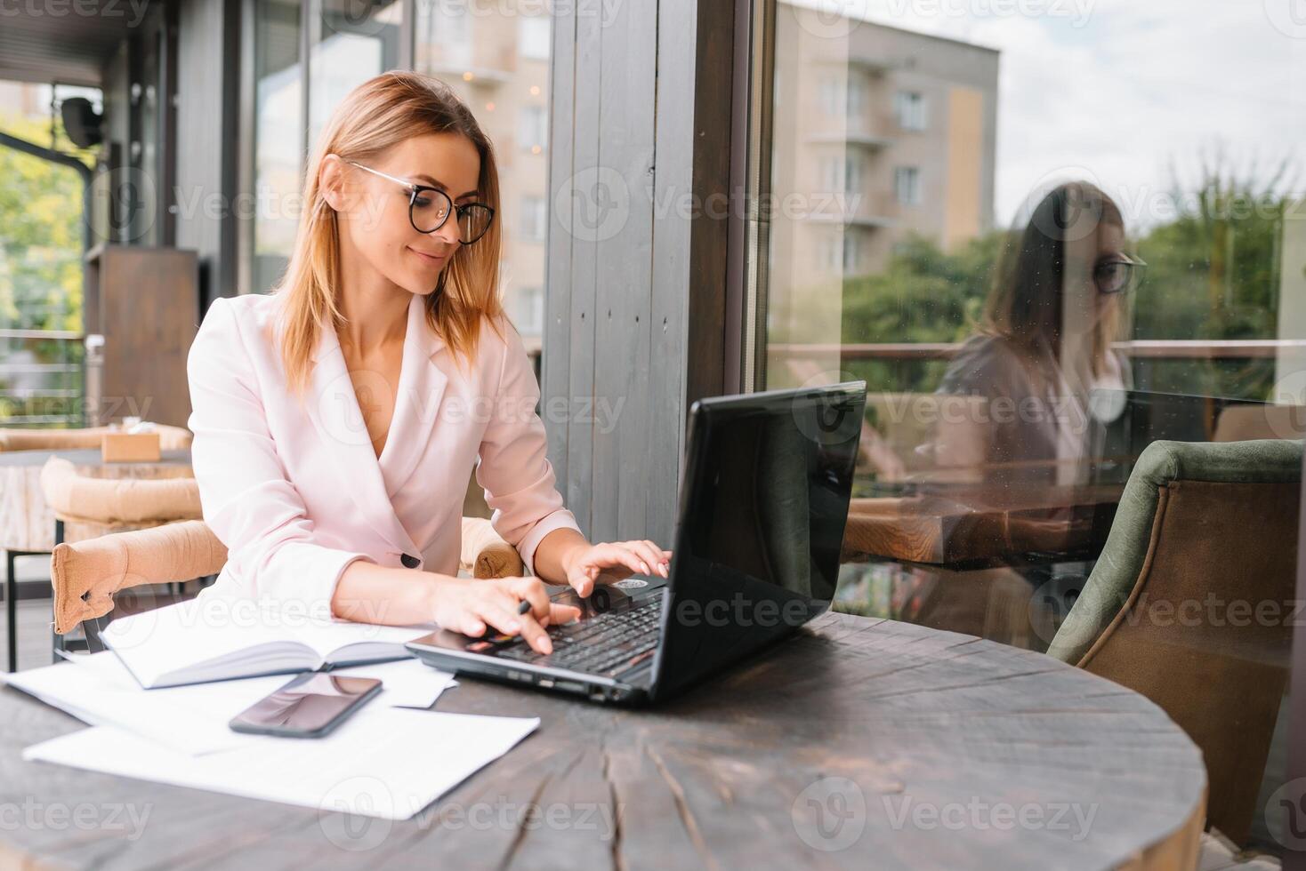 Portrait of young attractive businesswoman examining paperwork in bight light office interior sitting next to the window, business woman read some documents before meeting, filtered image. photo