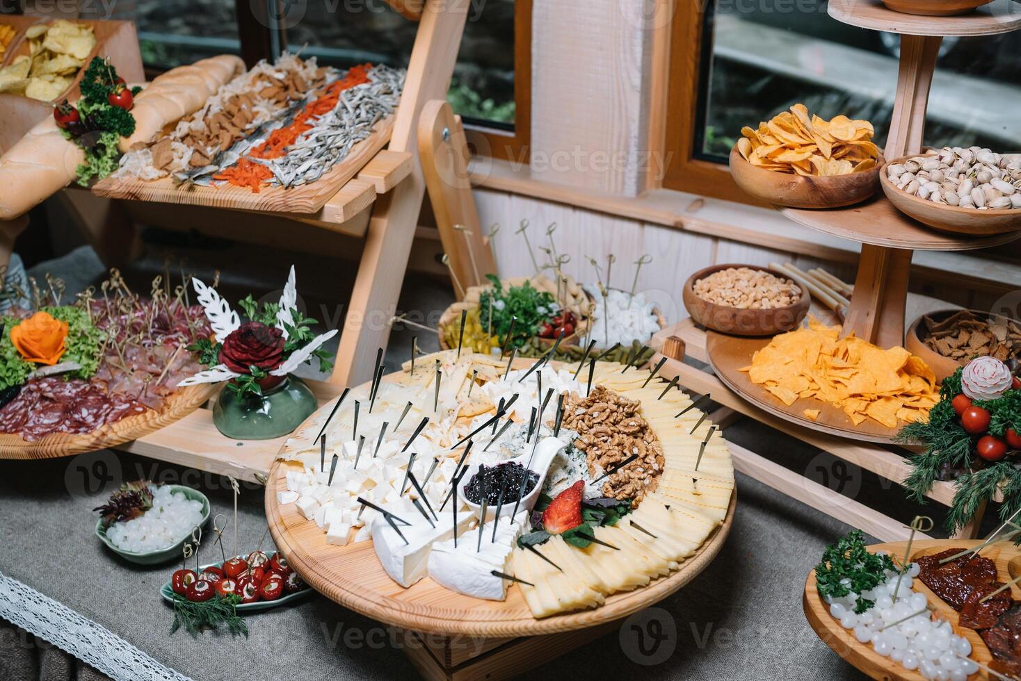 Antipasti board with various cheese and meat snacks with hummus and olives on wooden round board on black table photo