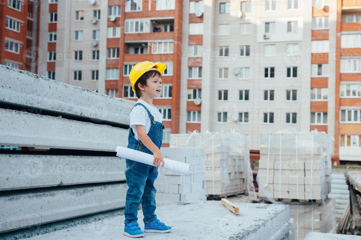 Architect in helmet writing something near new building. little cute boy on the building as an architect photo