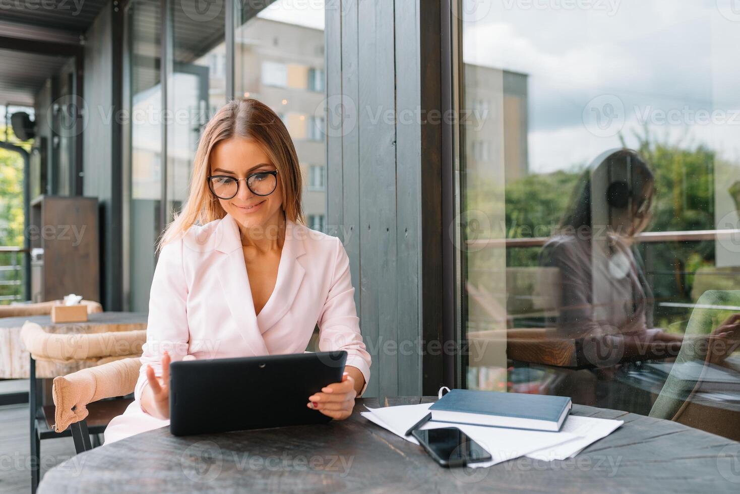 Portrait of young attractive businesswoman examining paperwork in bight light office interior sitting next to the window, business woman read some documents before meeting, filtered image photo