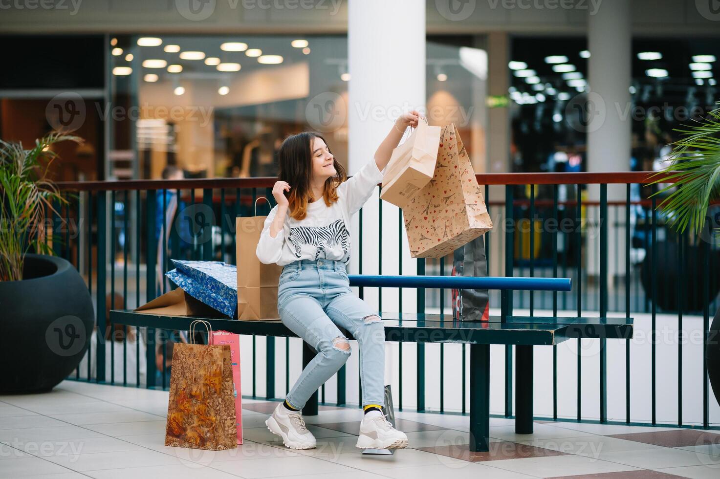 retail, gesture and sale concept - smiling teenage girl with many shopping bags at mall photo
