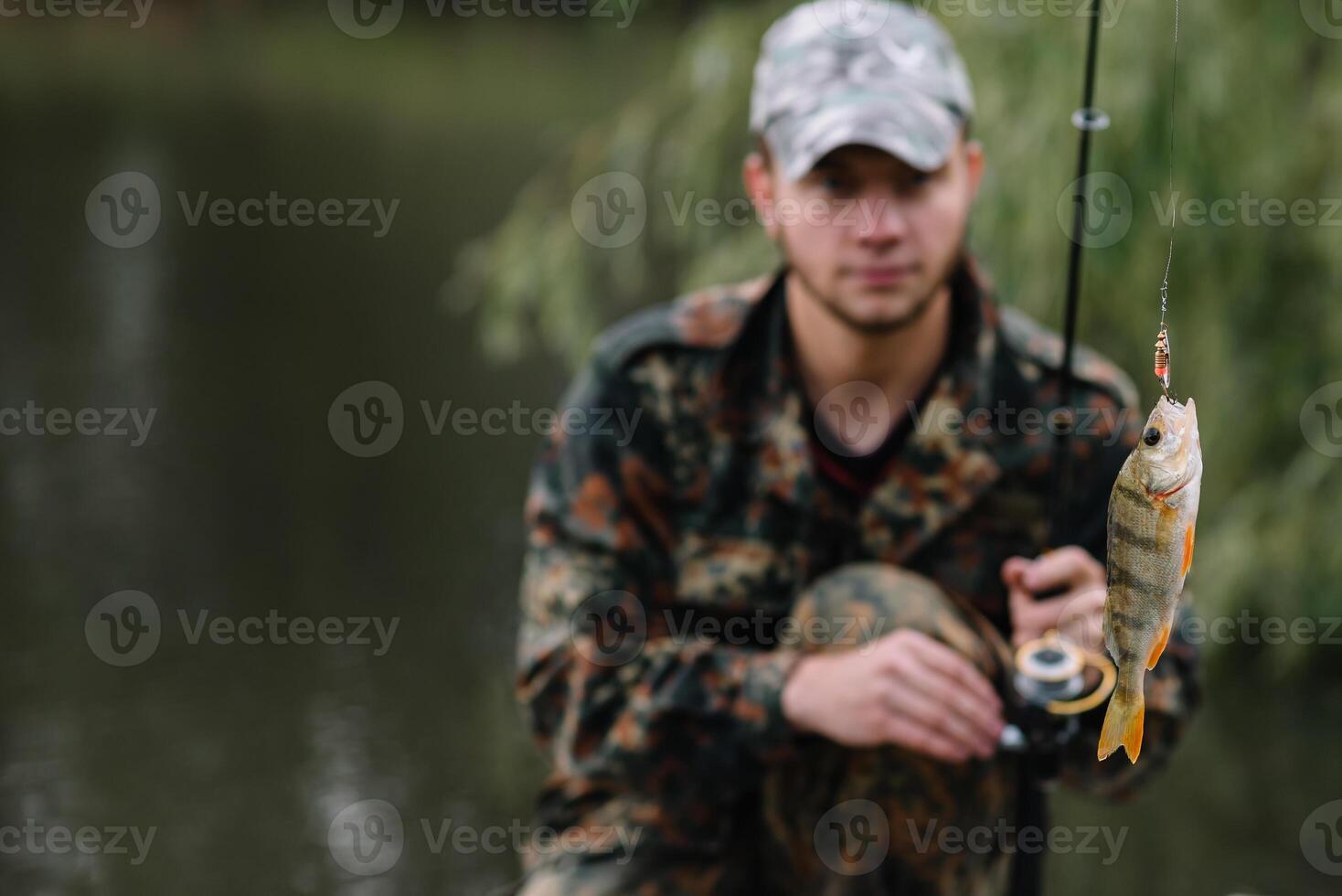 Fishing in river.A fisherman with a fishing rod on the river bank. Man fisherman catches a fish pike.Fishing, spinning reel, fish, Breg rivers. - The concept of a rural getaway. Article about fishing photo