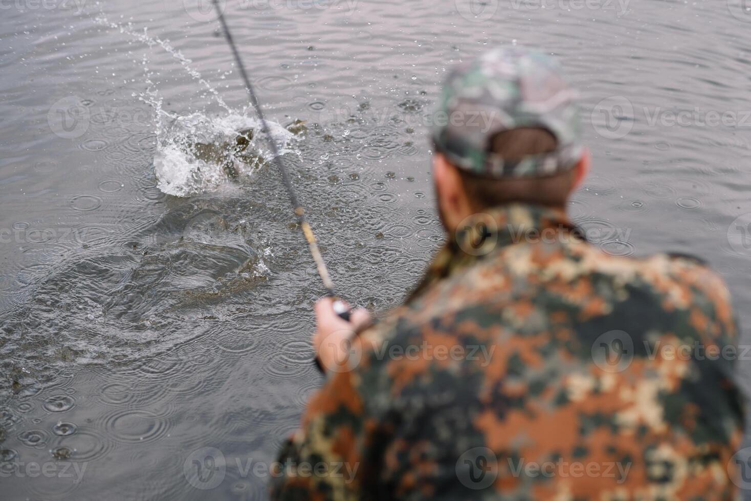 Fishing in river.A fisherman with a fishing rod on the river bank. Man fisherman catches a fish pike.Fishing, spinning reel, fish, Breg rivers. - The concept of a rural getaway. Article about fishing photo