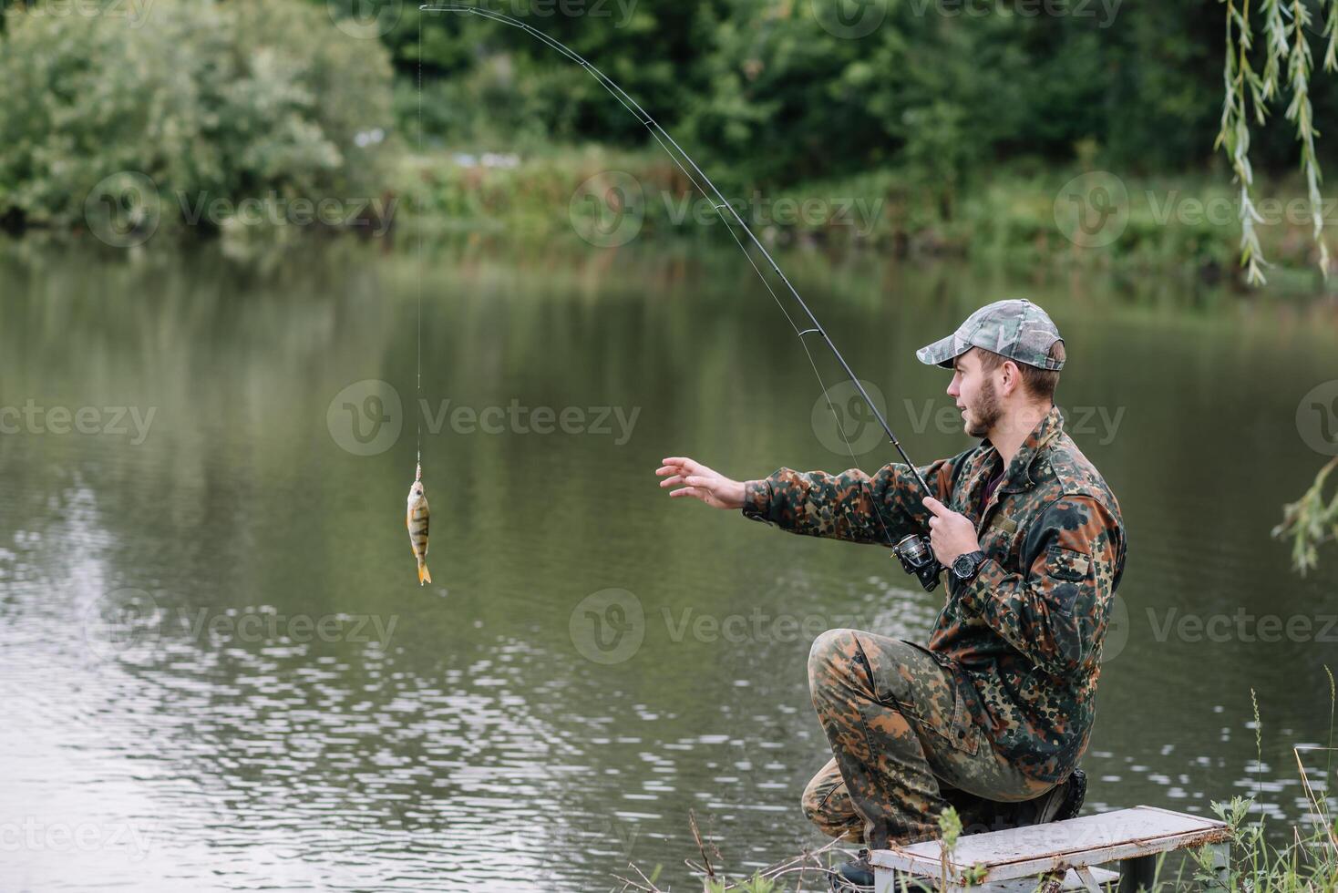 pescar en rio.a pescador con un pescar varilla en el río banco. hombre pescador capturas un pescado pesca del lucio, hilado carrete, pez, breg ríos - el concepto de un rural escapar. artículo acerca de pescar foto