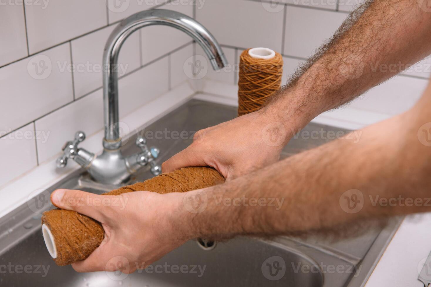 Hand holding dirty water filter cartridge over the sink. Brown coloring. Evidence of contamination of tap water with iron cations photo