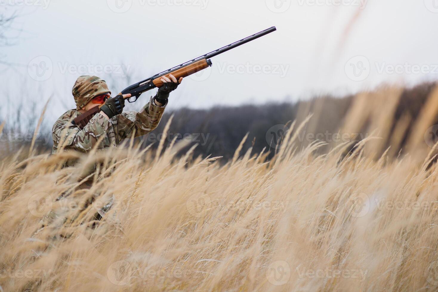 un masculino cazador con un pistola mientras sentado toma objetivo a un bosque. el concepto de un exitoso caza, un experimentado cazador. caza el otoño estación. el cazador tiene un rifle y un caza uniforme foto