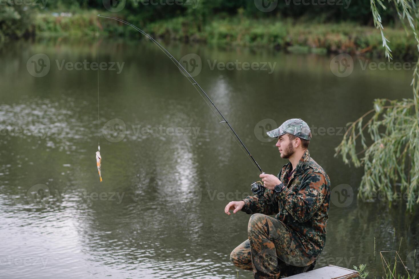 Fishing in river.A fisherman with a fishing rod on the river bank. Man fisherman catches a fish pike.Fishing, spinning reel, fish, Breg rivers. - The concept of a rural getaway. Article about fishing photo