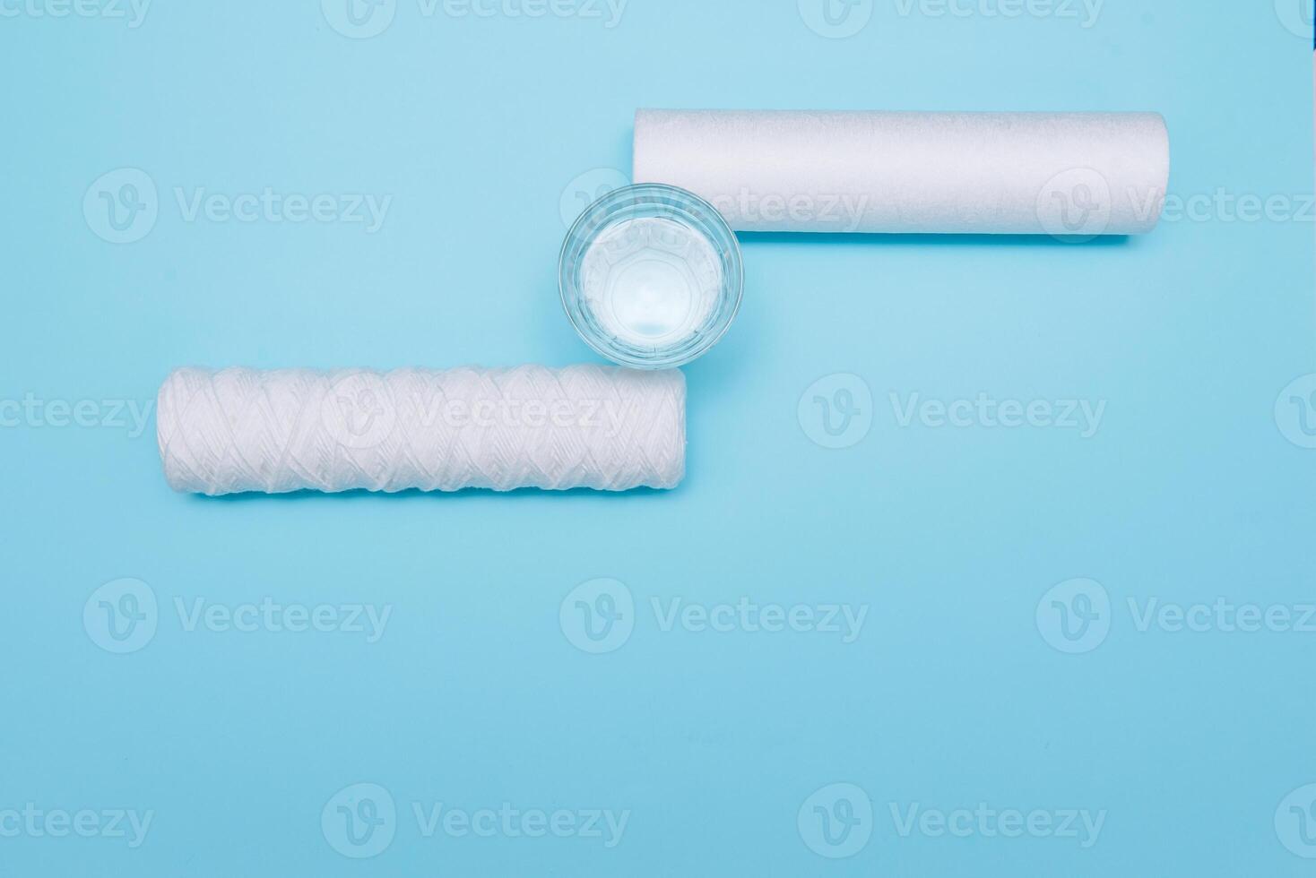 Water filters. Carbon cartridges and a glass with water on a blue background. Household filtration system photo