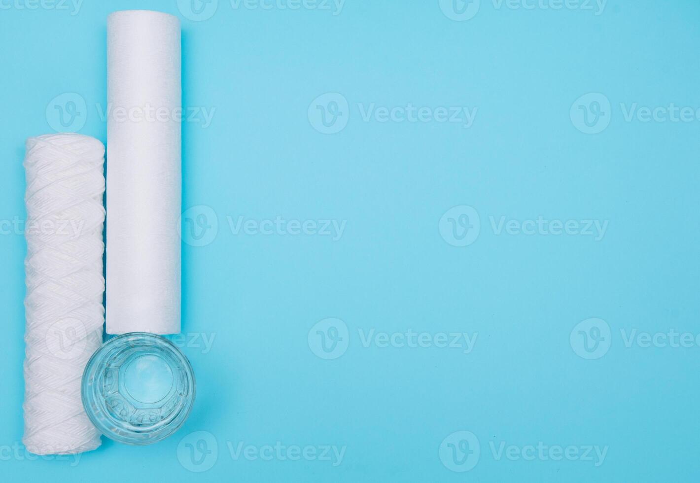 Water filters. Carbon cartridges and a glass with water on a blue background. Household filtration system photo