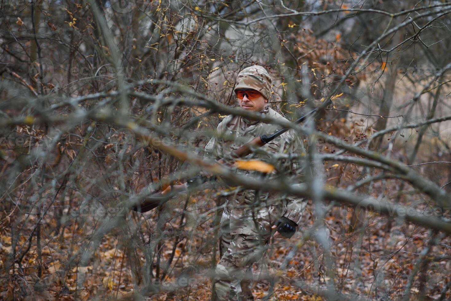 hunting, war, army and people concept - young soldier, ranger or hunter with gun walking in forest photo