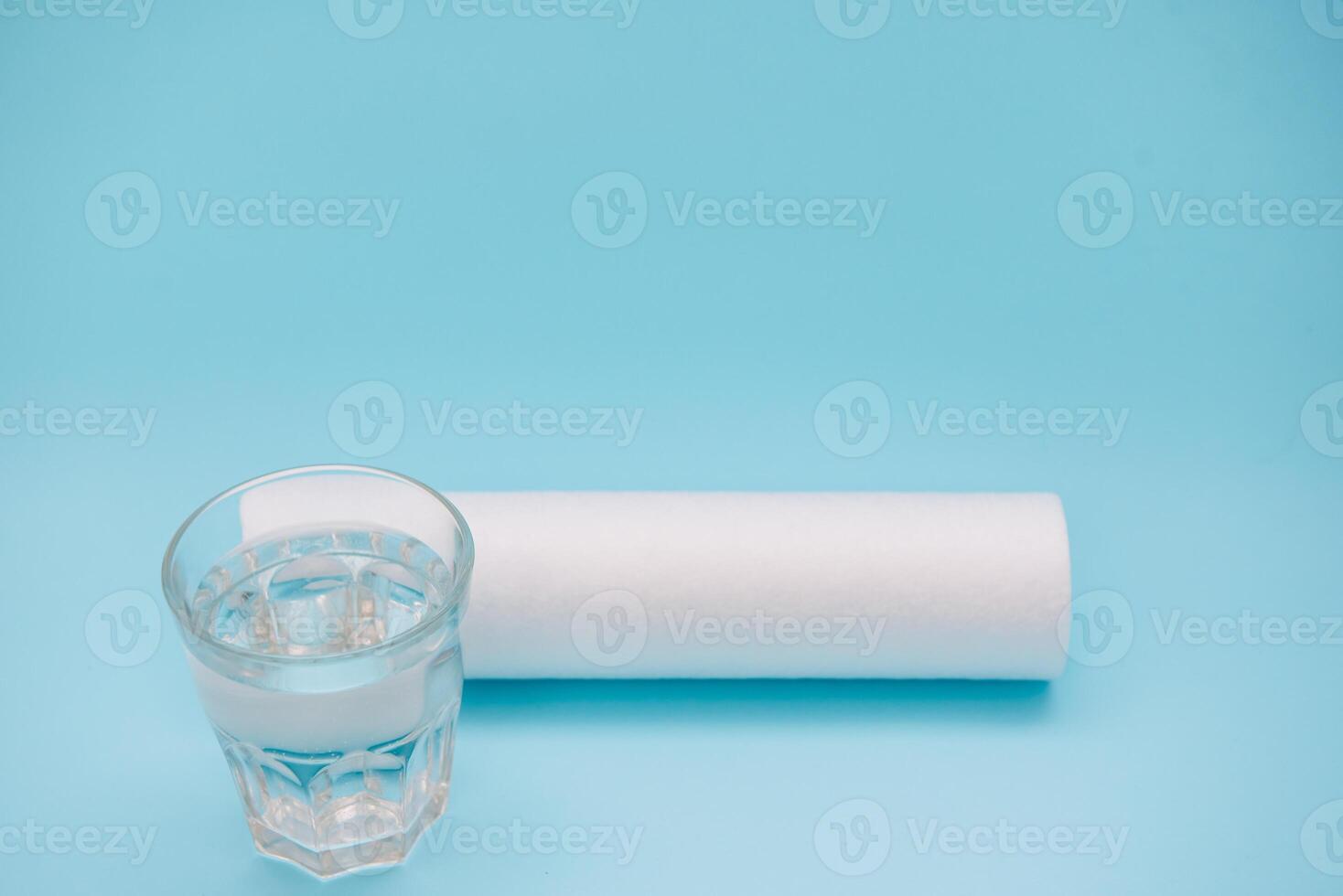 Water filters. Carbon cartridges and a glass with water on a blue background. Household filtration system photo