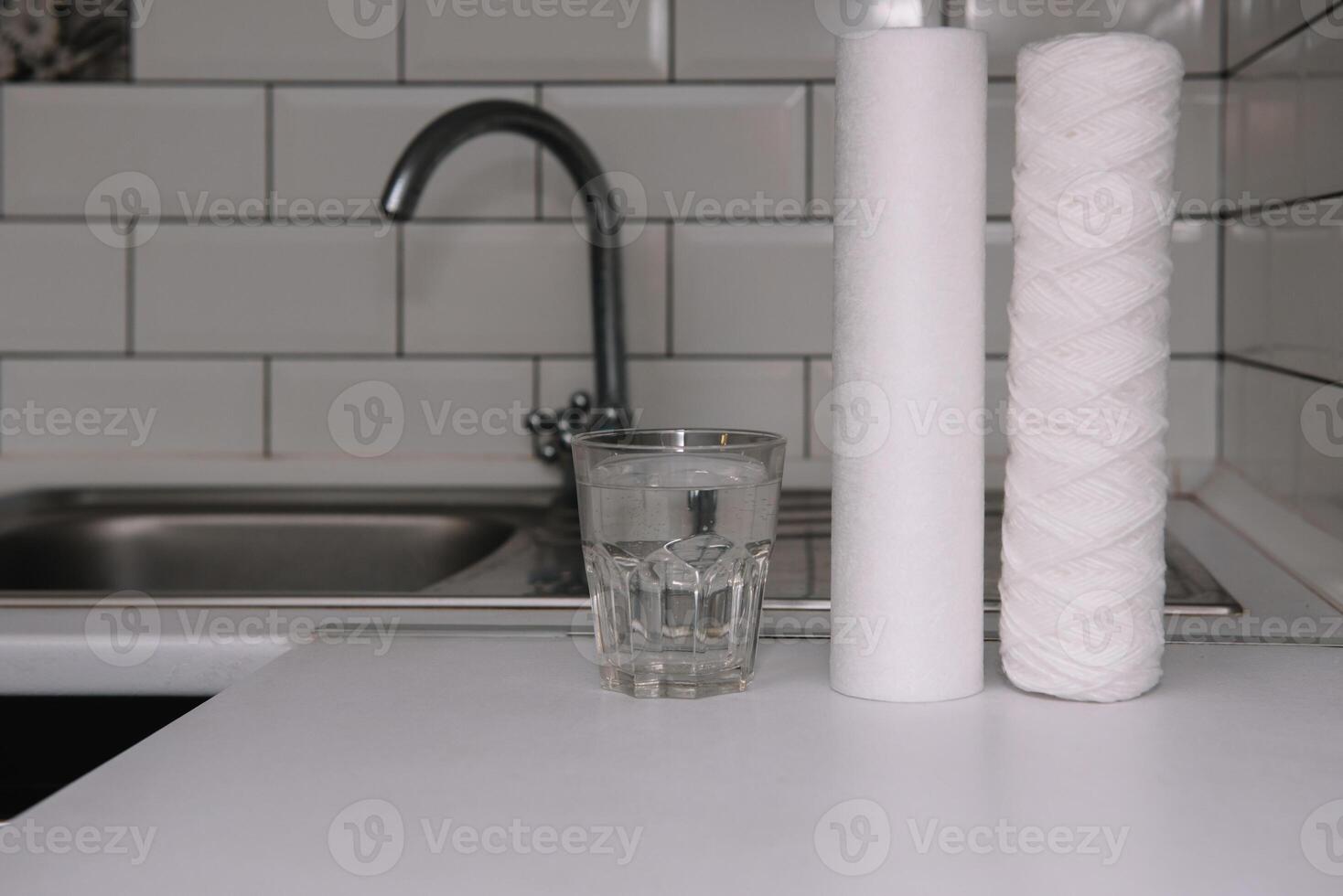 Water filters. Carbon cartridges and a glass on a white kitchen background. Household filtration system photo