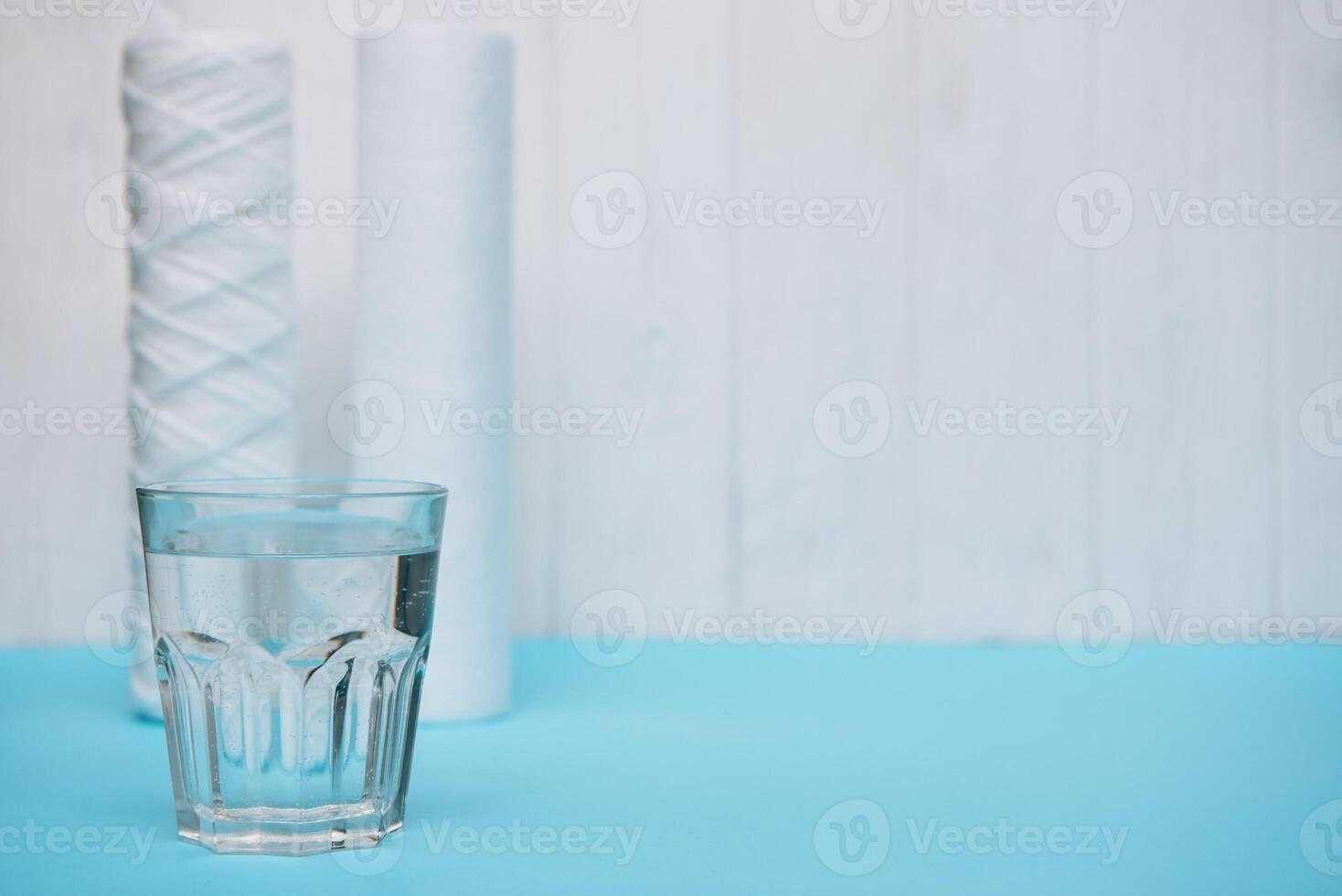 Water filters. Carbon cartridges and a glass on a white blue background. Household filtration system photo