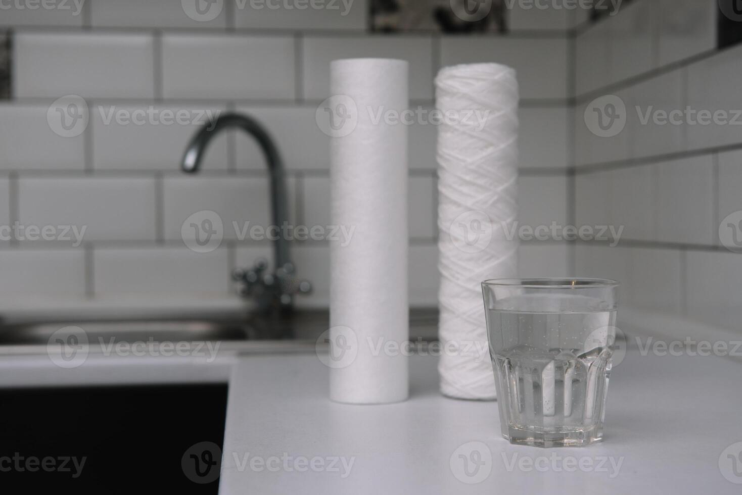 Water filters. Carbon cartridges and a glass on a white kitchen background. Household filtration system photo