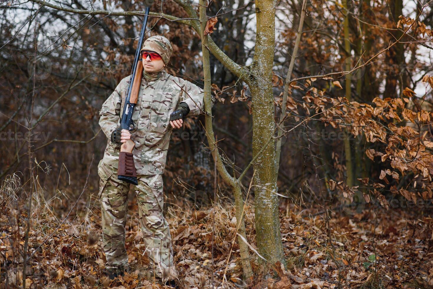 hunting, war, army and people concept - young soldier, ranger or hunter with gun walking in forest photo