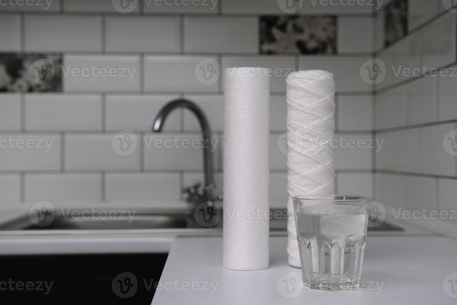 Water filters. Carbon cartridges and a glass on a white kitchen background. Household filtration system photo