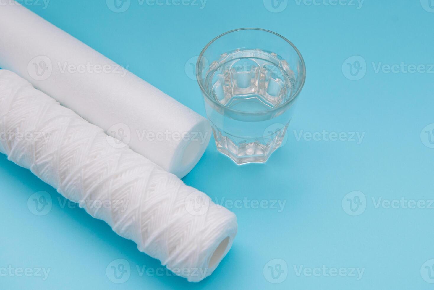 Water filters. Carbon cartridges and a glass with water on a blue background. Household filtration system photo