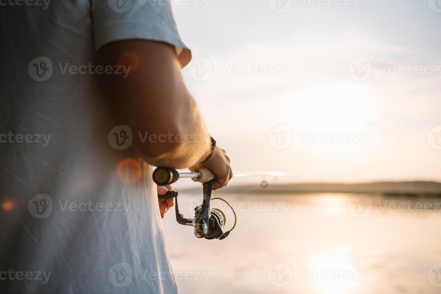 The fisherman's hands, holds the spinning rod, rotates the coil handle. Hobby and activity. photo