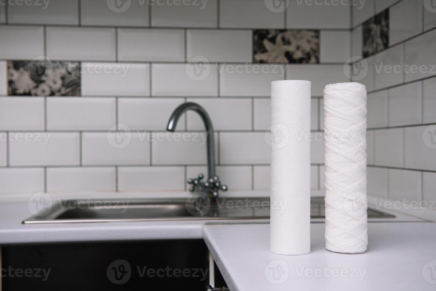 Water filters. Carbon cartridges and a glass on a white kitchen background. Household filtration system photo