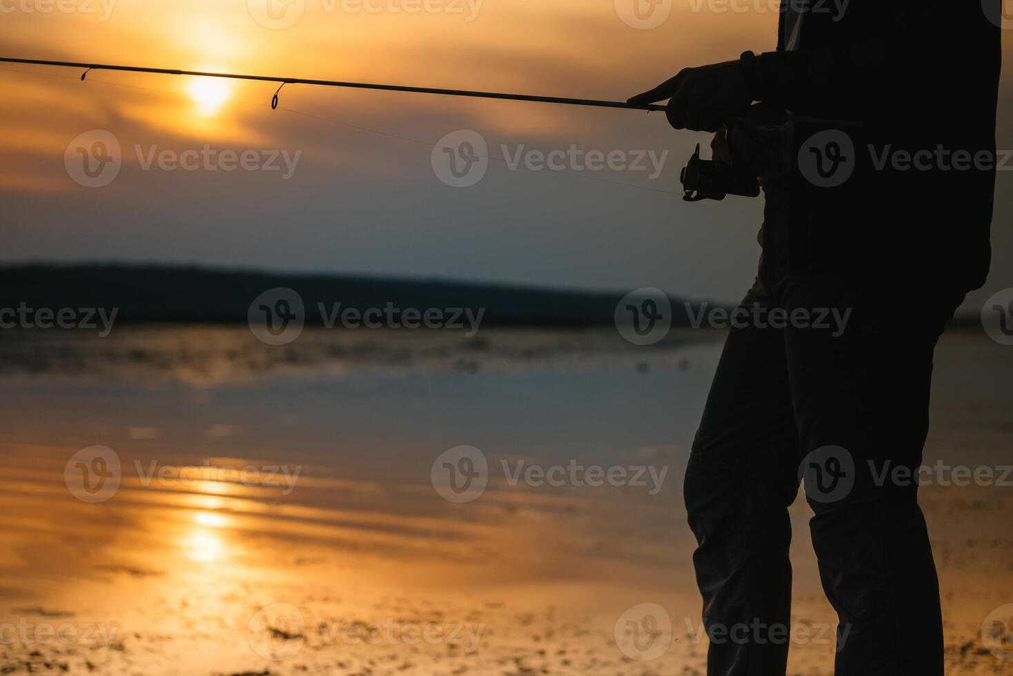 The fisherman's hands, holds the spinning rod, rotates the coil handle. Hobby and activity. photo