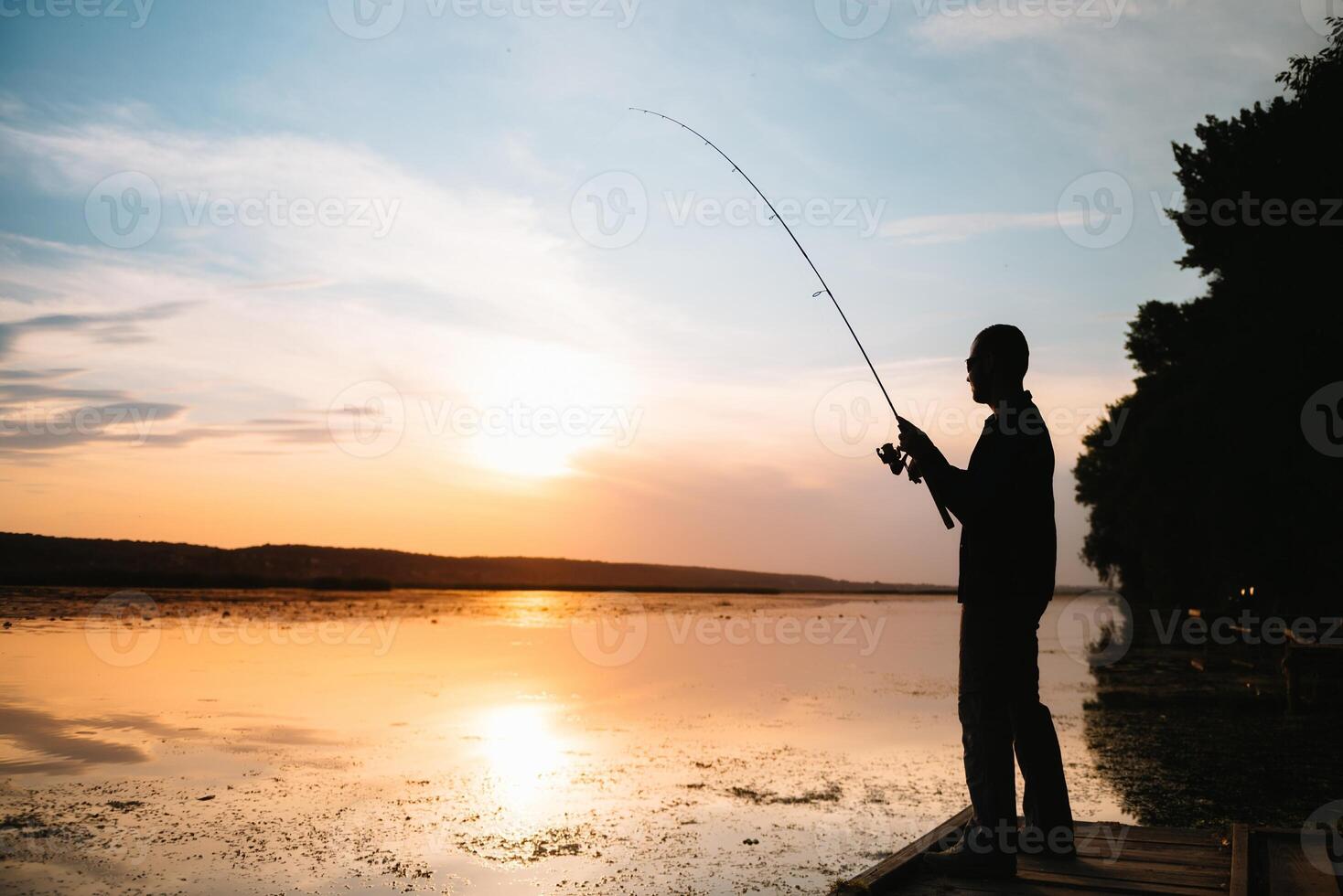 Fishing. spinning at sunset. Silhouette of a fisherman. photo