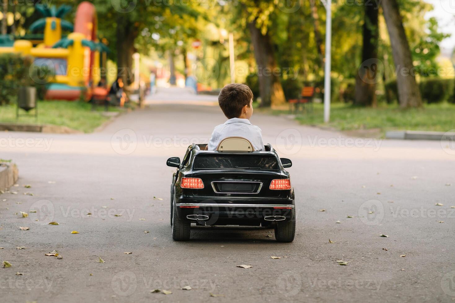 Cute boy in riding a black electric car in the park. Funny boy rides on a toy electric car. Copy space. photo