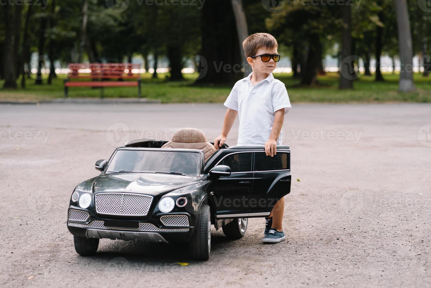 Cute boy in riding a black electric car in the park. Funny boy rides on a toy electric car. Copy space. photo