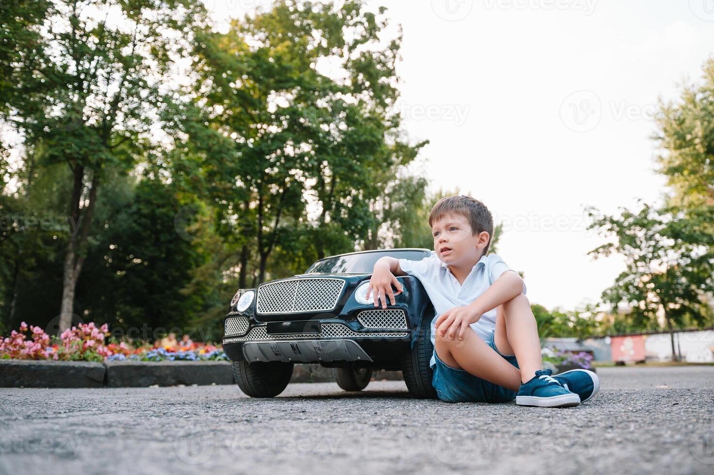 Cute boy in riding a black electric car in the park. Funny boy rides on a toy electric car. Copy space. photo