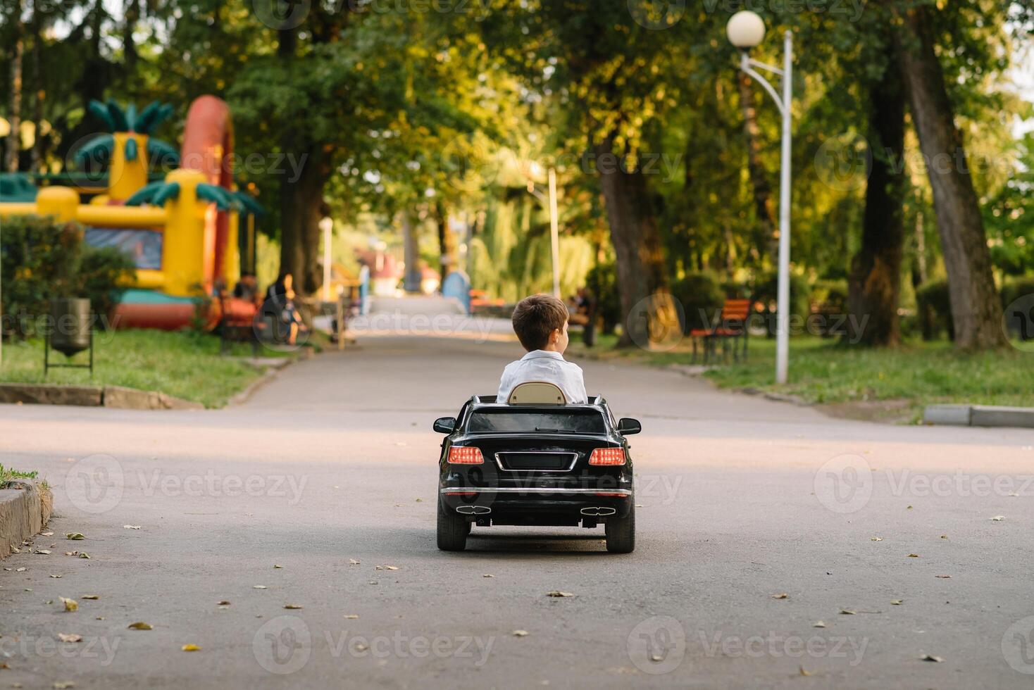 Cute boy in riding a black electric car in the park. Funny boy rides on a toy electric car. Copy space. photo