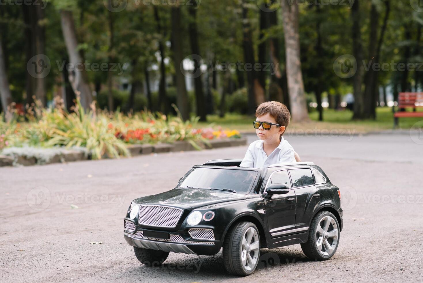 linda chico en montando un negro eléctrico coche en el parque. gracioso chico paseos en un juguete eléctrico coche. Copiar espacio. foto