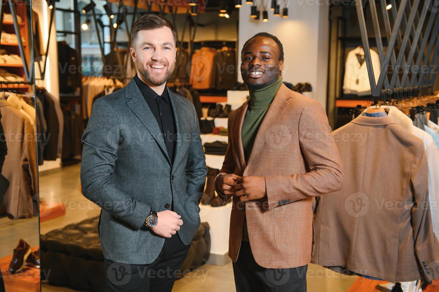 dos elegante multirracial hombres en pie en clásico trajes en pie en un ropa Tienda foto