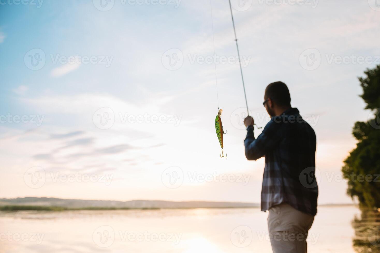 Young man fishing at misty sunrise. photo