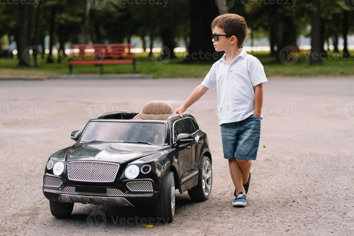 Cute boy in riding a black electric car in the park. Funny boy rides on a toy electric car. Copy space. photo