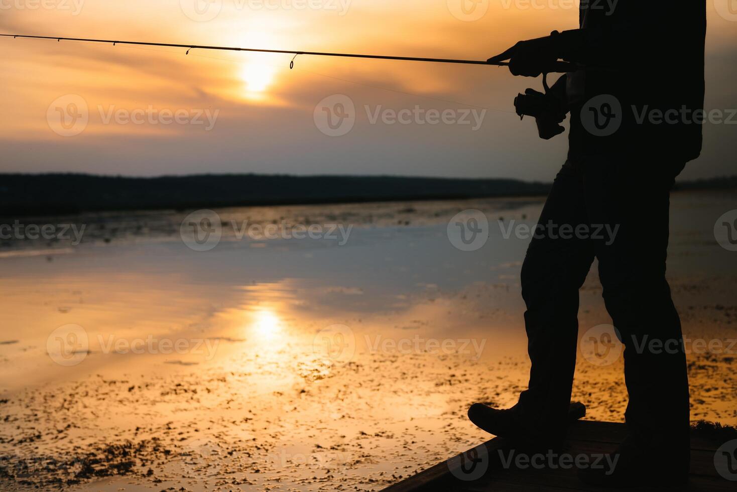 The fisherman's hands, holds the spinning rod, rotates the coil handle. Hobby and activity. photo