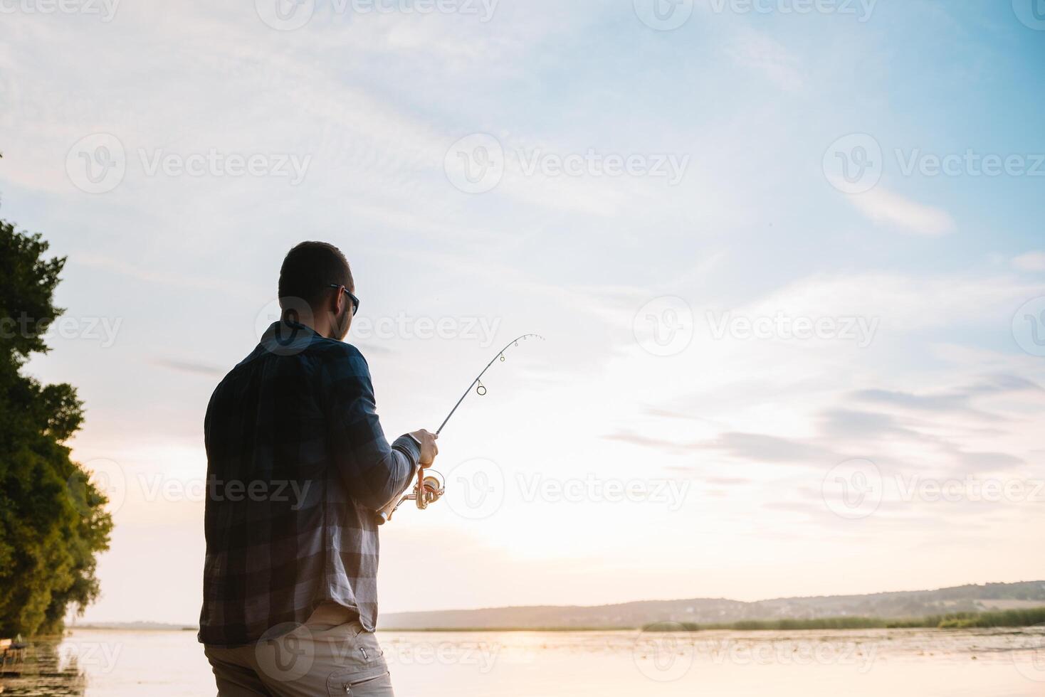 Young man fishing at misty sunrise. photo