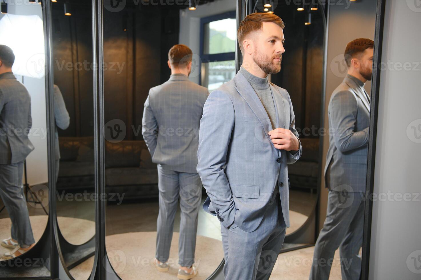 Man trying on suit jacket at mirror in menswear shop photo