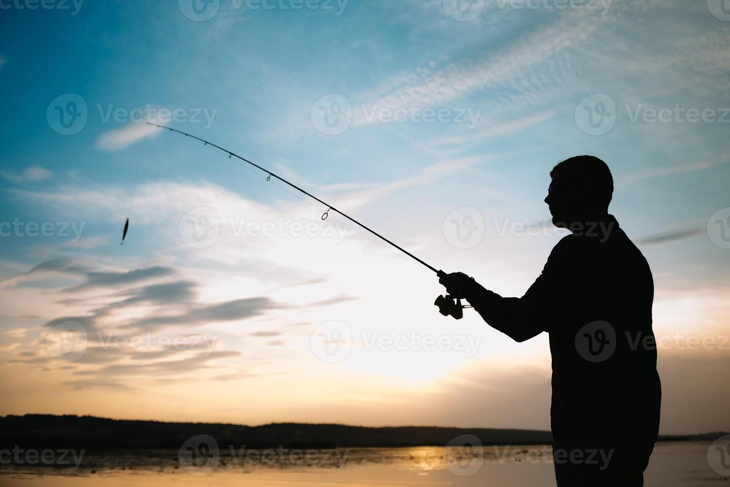 Fishing. spinning at sunset. Silhouette of a fisherman. photo