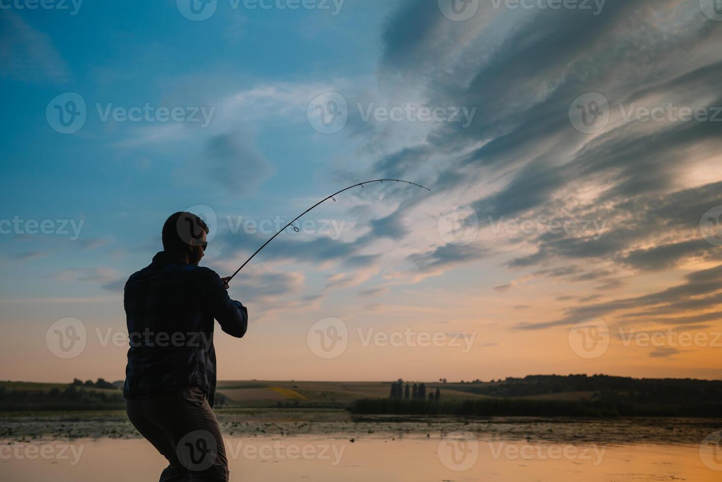 Fishing. spinning at sunset. Silhouette of a fisherman. photo