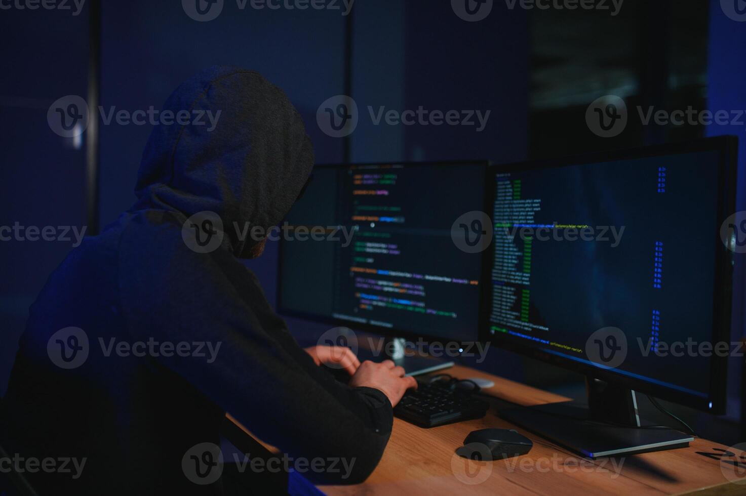 hacker sitting at desk in dark atmosphere. A computer programmer or hacker. Anonymous computer hacker. photo