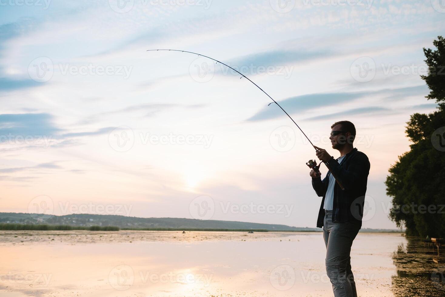 pescador hombre pescar con hilado varilla en un río banco a brumoso brumoso amanecer. pescador con hilado. hilado concepto. foto