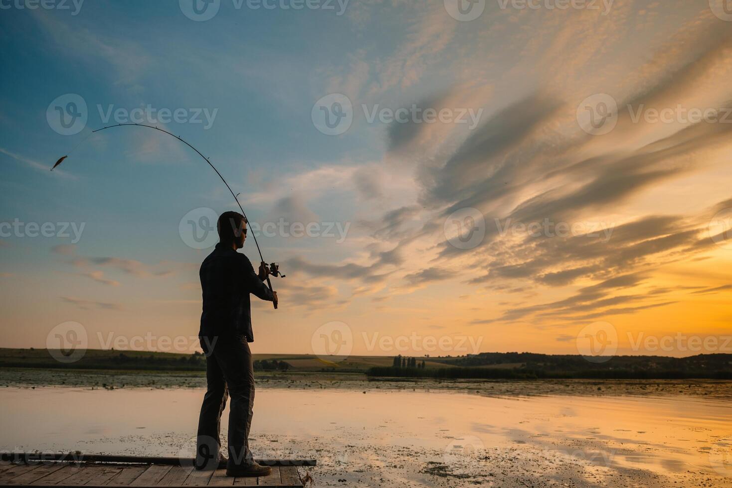 Fisherman at sunset on the river .Beautiful summer landscape with sunset on the river photo