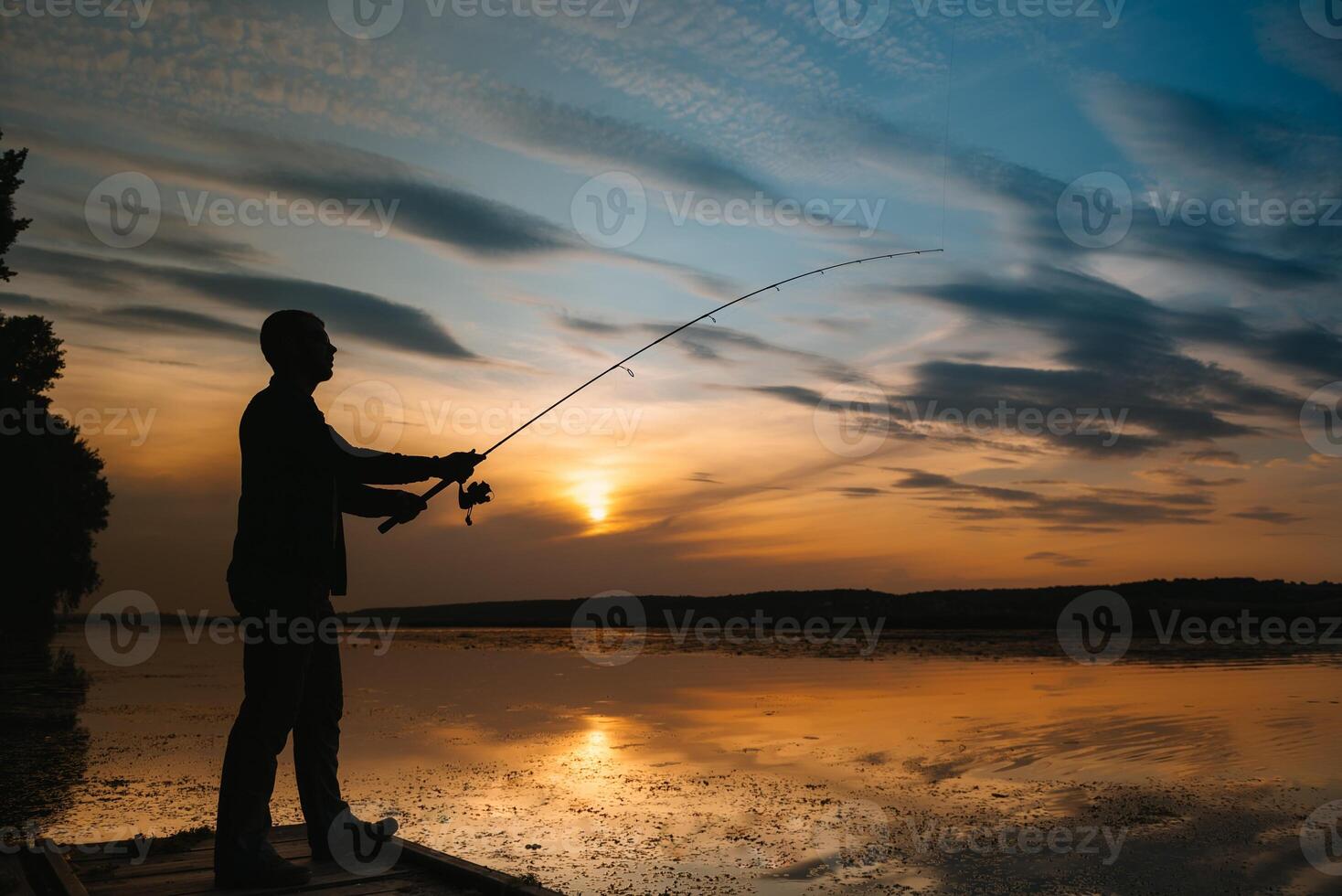 A fisherman silhouette fishing at sunset. Freshwater fishing, catch of fish. photo