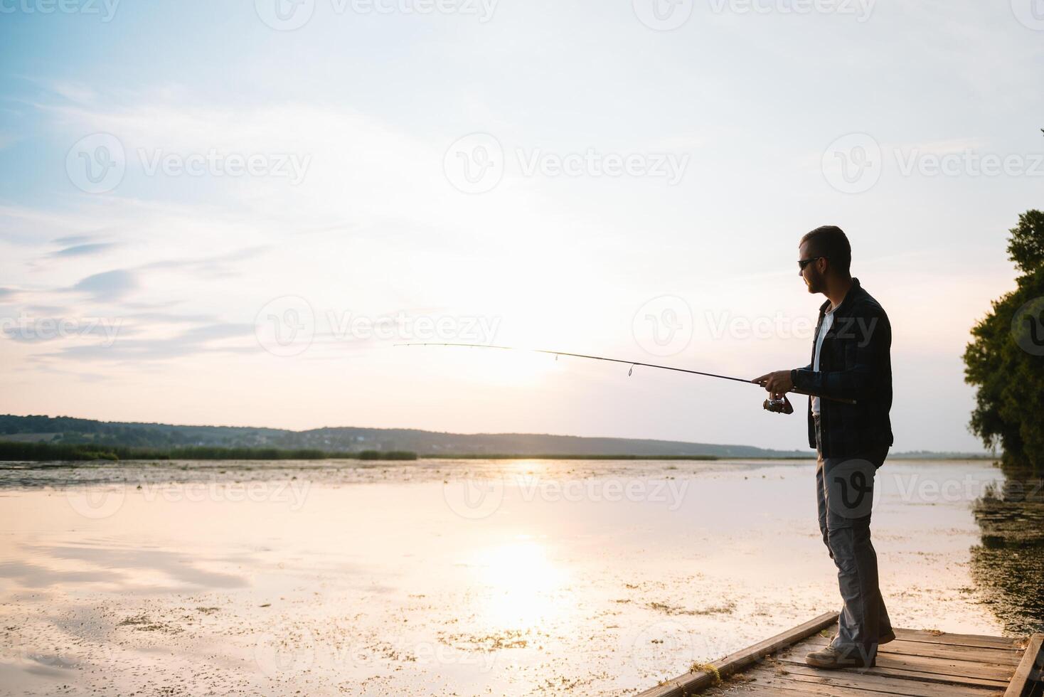 Young man fishing at misty sunrise. photo