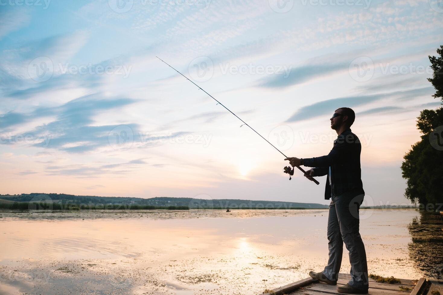 Young man fishing at misty sunrise. photo