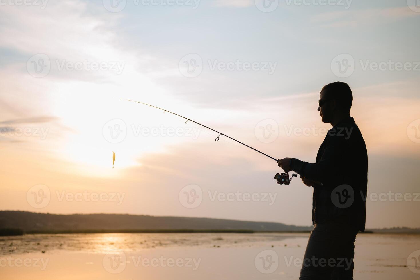 Young man fishing at misty sunrise. photo